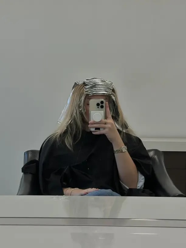 Person taking a mirror photo at a hair salon